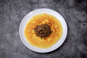 Minced meat filling on a large thin pancake. Making a pancake filled with meat or heart