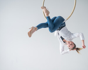 Caucasian woman in casual clothes on an aerial hoop. 