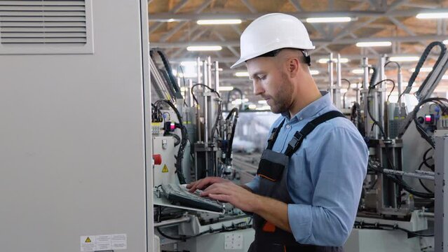 Operator of machine. Industrial worker wearing safety uniform and helmet indoors in factory