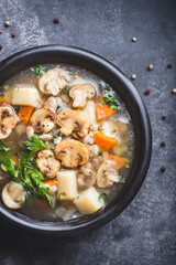 Transparent soup with champignon mushrooms, vegetables and pearl barley. Simple and hearty cuisine for the cold season. Forest food, vegan proteins. Baltic cuisine, close up