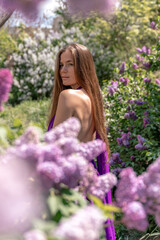 Obraz na płótnie Canvas portrait of young woman with long hair outdoors in blooming lilac garden