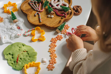 Child hands creating Christmas crafts. Child playing with play dough and Christmas decorations. Holiday Art Activity for Kids. Sensory play for toddlers.