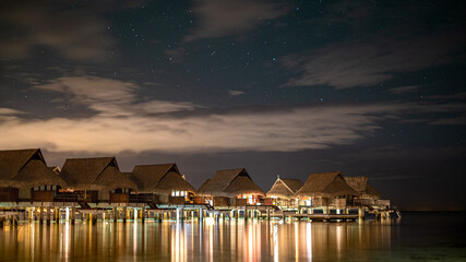 Apartments over the water at night with clouds and starry sky in French Polynesia