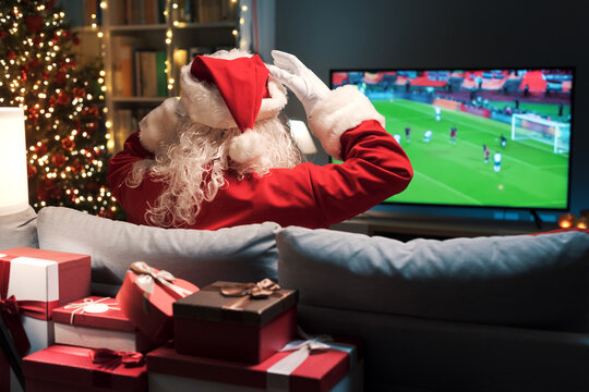 Cheerful Santa Claus watching football on TV