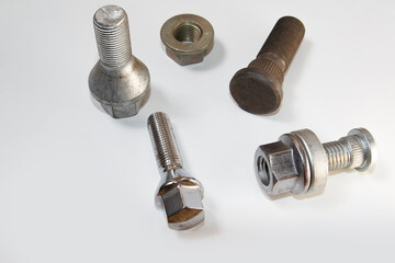 Different bolts with nuts scattered on a white background. Bolts on a white background