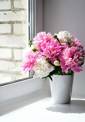 A view of a bouquet of pink peonies standing in a vase on the window. Concept background, flowers, holiday