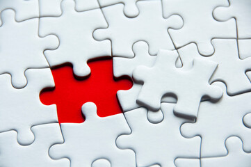 White jigsaw puzzle on red cover background with customizable space for text or idea. Copy space