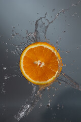 Fototapeta na wymiar orange in splash of water on a gray background