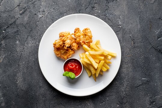 Top view of aesthetically decorated delicious chicken nagets with french fries on the gray surface