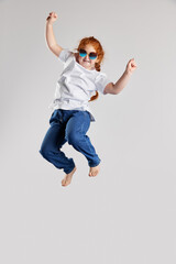 Delight. Happy little girl, kid in white t-shirt and jeans jumping high isolated over white background. Kids fashion, emotions, carefree childhood