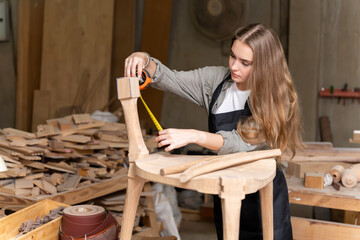 A female carpenter assembling a chair she had designed and built. At the furniture factory found inside her house