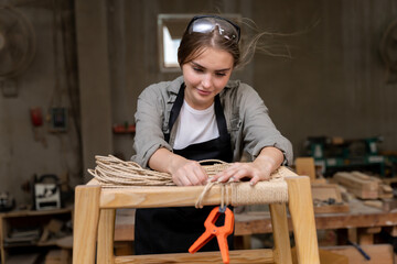 A female carpenter assembling a chair she had designed and built. At the furniture factory found...