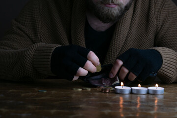 European poor bearded man counting euro coins during energy crisis in Europe. A worried man in warm...
