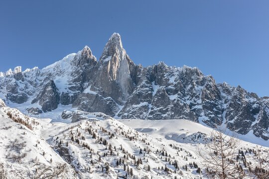 Low-angle closeup of Aiguille du Dru snowy mountain peak with clear sky background