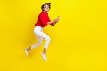 Full body portrait of excited sporty lady jumping hold use telephone run isolated on yellow color background