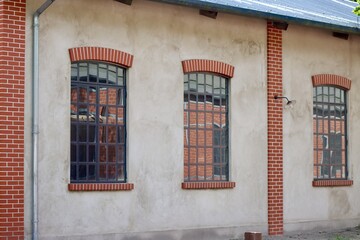 Fototapeta na wymiar Fond de Gras - historic building in steam train station, white walls with red brick decorations and grilles on windows
