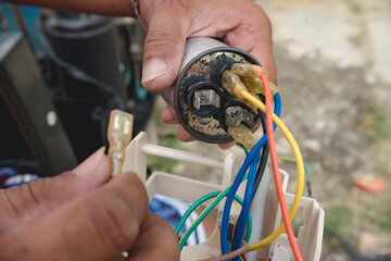 An AC technician removes a defective capacitor from a window type air conditioner control panel. - obrazy, fototapety, plakaty