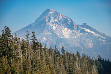 Mt Hood rises in the distance over Lost Lake in Oregon mid-afternoon.  The blue lake and green pine trees from the majestic mountain. 