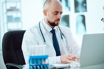 scientist works on a laptop while sitting at a table in a medical laboratory.