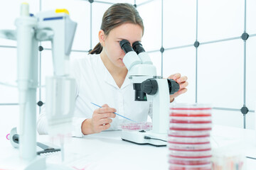 young female student examines samples of genetically modified bacteria to decompose plastic