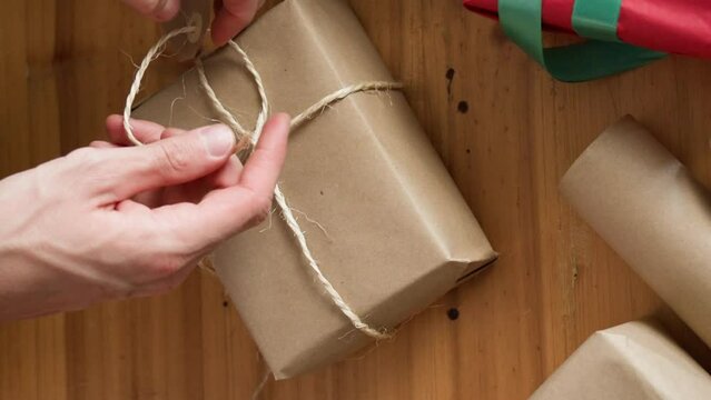 Man wrapping Christmas gift with twine and gift tag.. Christmas or New year DIY packing Concept. 