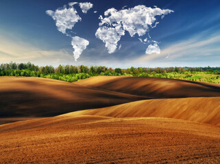 clouds in the form of a map of the world over the field. Travel and landscape concept. hilly field
