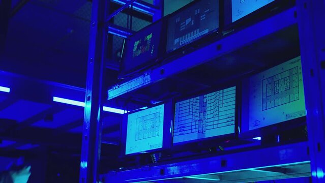 Engineers , partners , architects or businessmen in black suits discussing , analyzing , looking or watching project . A lot of monitors inside dark place . Concept of security systems or engineering