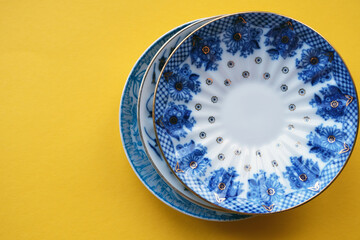 Vintage plates with blue drawings on a yellow background, top view
