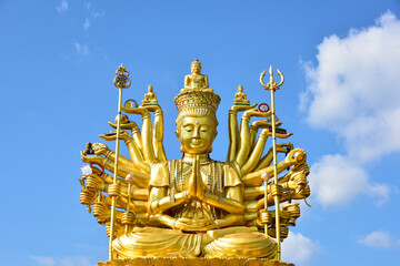 Big Golden Guan Yim or brass statue of Guanyin on a bright sky background. is the Goddess of Mercy...