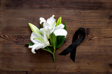 Mourning or funeral concept with white liles and black ribbon