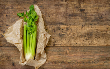 Celery in paper packaging on old wooden table