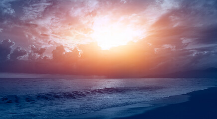 Naklejka na ściany i meble Calm sea waves crushing on sandy coast with cloudy dramatic sunset sky over the sea