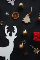 Small presents, various Christmas ornaments and deer figurine on dark background. Top view.