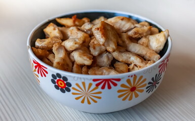 Pieces of fried chicken in a ceramic cup close-up on the background of a light kitchen table