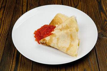 delicious pancakes with red caviar on a plate.
