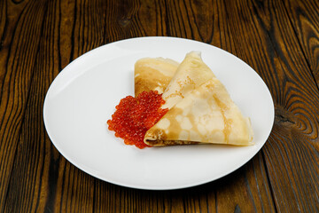delicious pancakes with red caviar on a plate.
