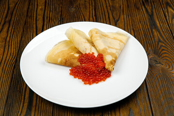 delicious pancakes with red caviar on a plate.
