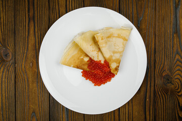 delicious pancakes with red caviar on a plate.
