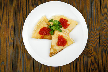 delicious pancakes with red caviar on a plate.
