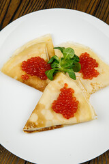delicious pancakes with red caviar on a plate.
