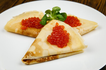 delicious pancakes with red caviar on a plate.
