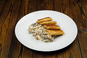 delicious pancakes with fried mushrooms on a plate.
