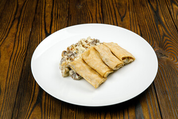 delicious pancakes with fried mushrooms on a plate.
