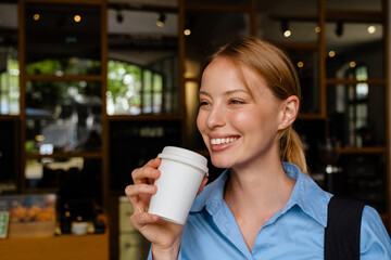Ginger white woman drinking coffee while using cellphone at cafe