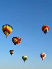 Verticaal schot van kleurrijke heteluchtballonnen in een blauwe lucht