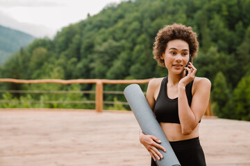 Curly woman talking on cellphone after yoga practice