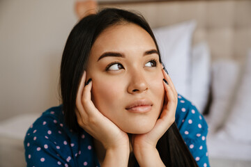 Portrait of young beautiful calm asian woman propping her head
