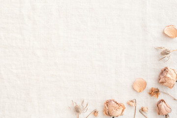 Decorative frame of beige pink roses with dried flowers placed on a light burlap background