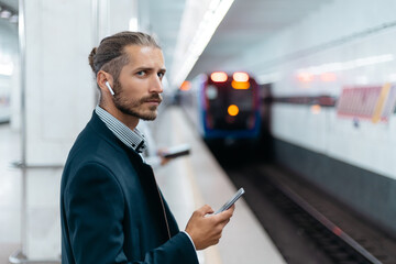 business man with a smartphone standing on the subway platform.