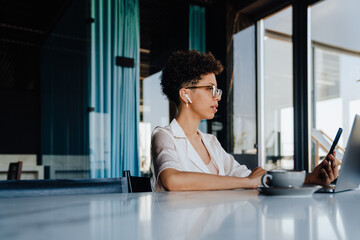 Middle-aged businesswoman using cellphone while working in office